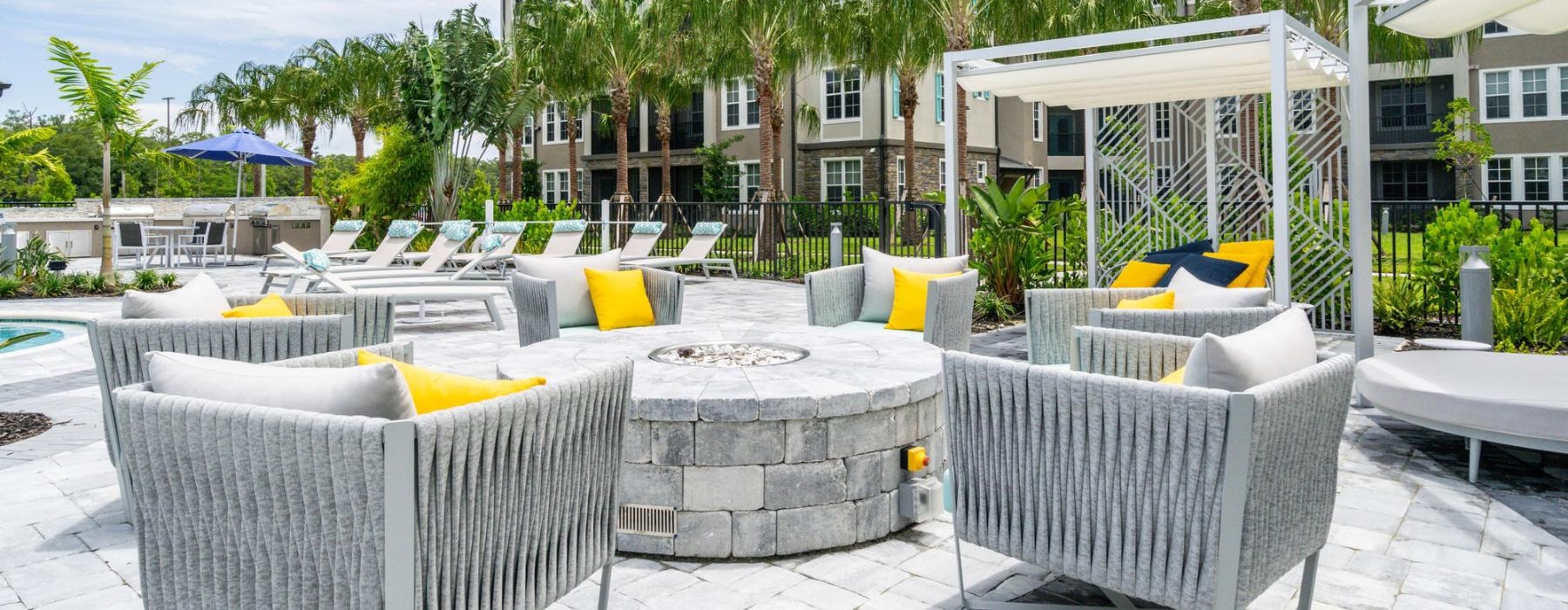 a patio with chairs and tables and umbrellas and a building with trees